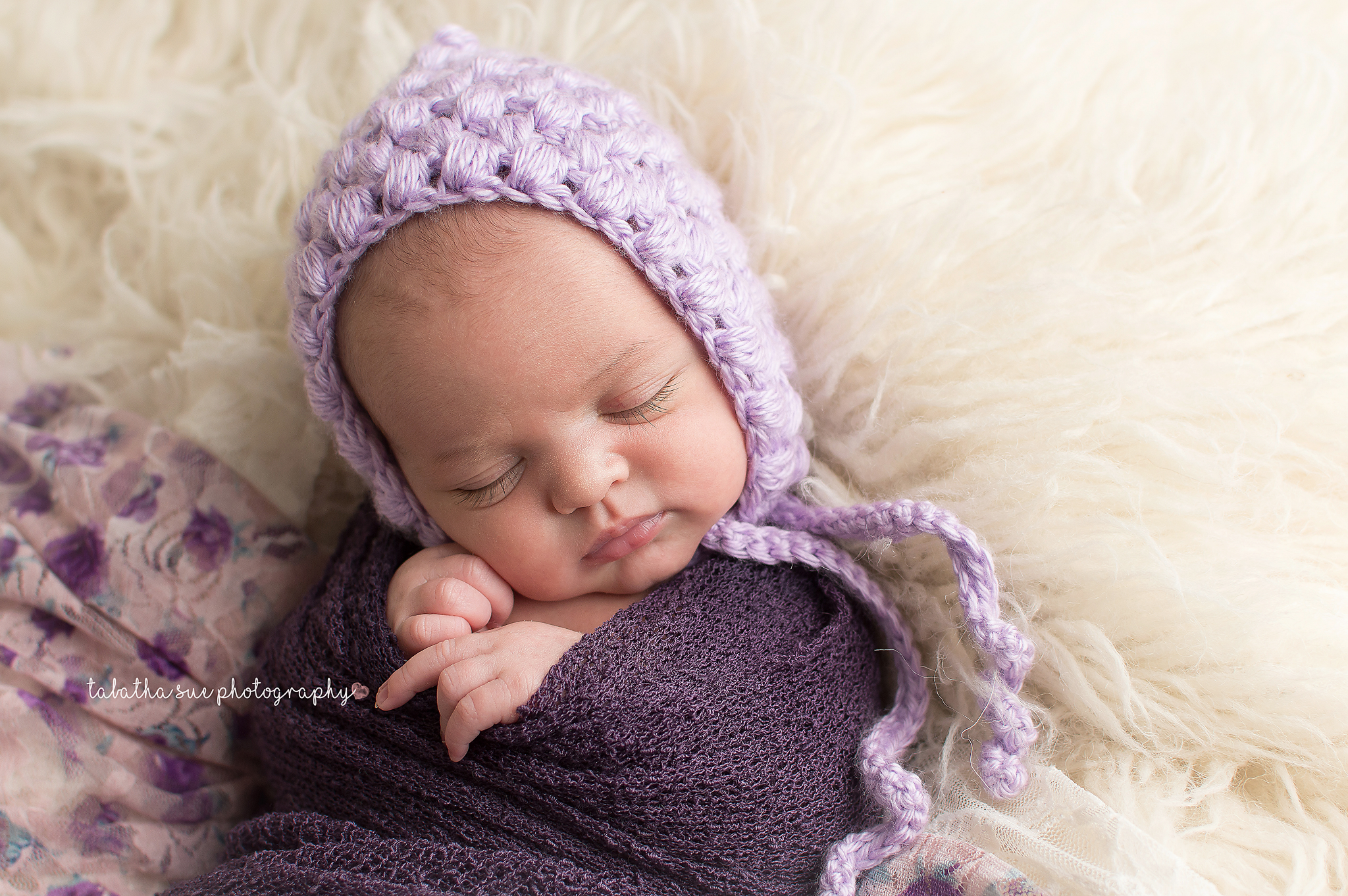 newborn-baby-pictures-wearing-purple-bonnet-and-purple-wrap-on-fur-best-newborn-photographer-in-cleveland-ohio.png
