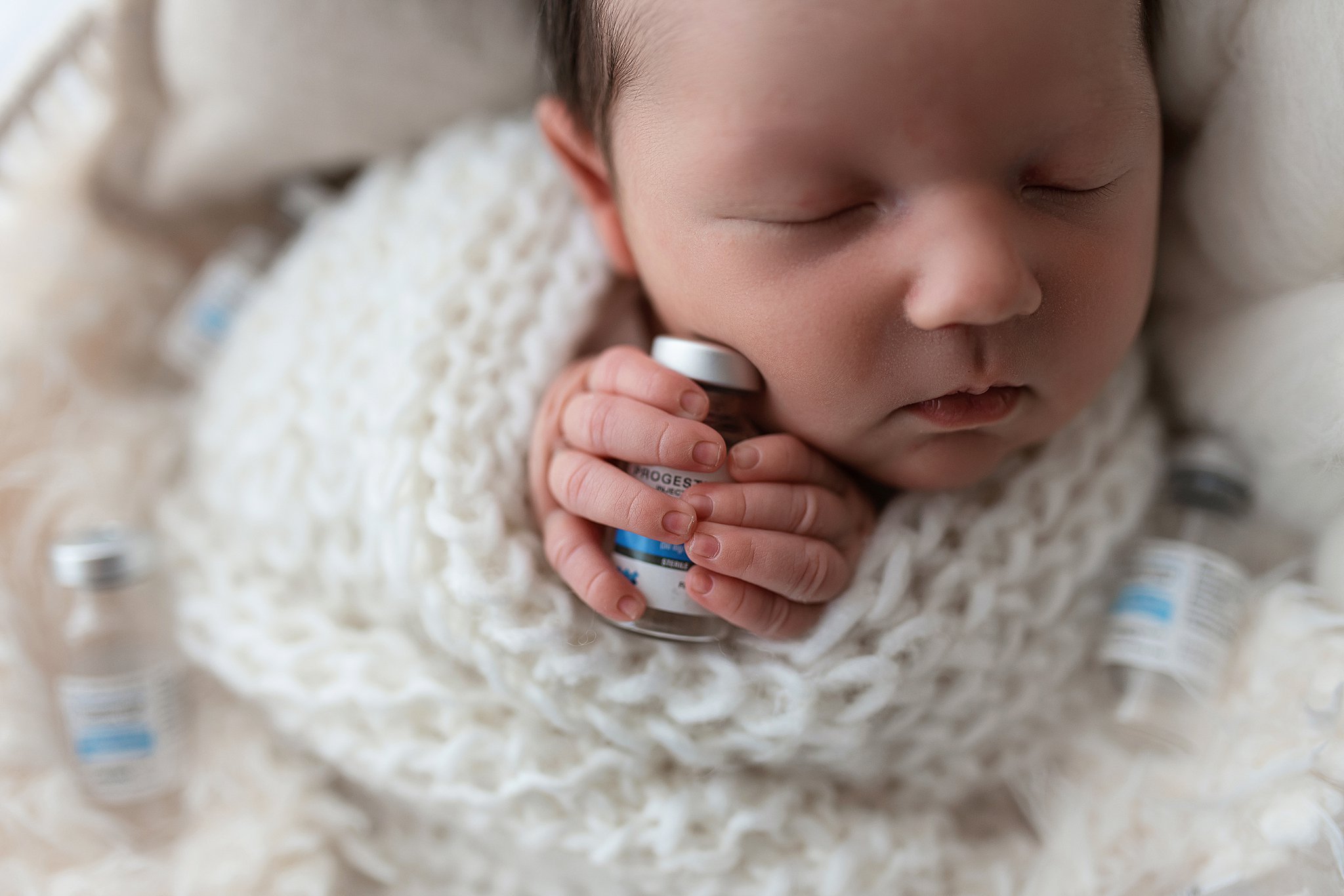 Details of a newborn baby holding a vial of progesterone doulas in cleveland ohio