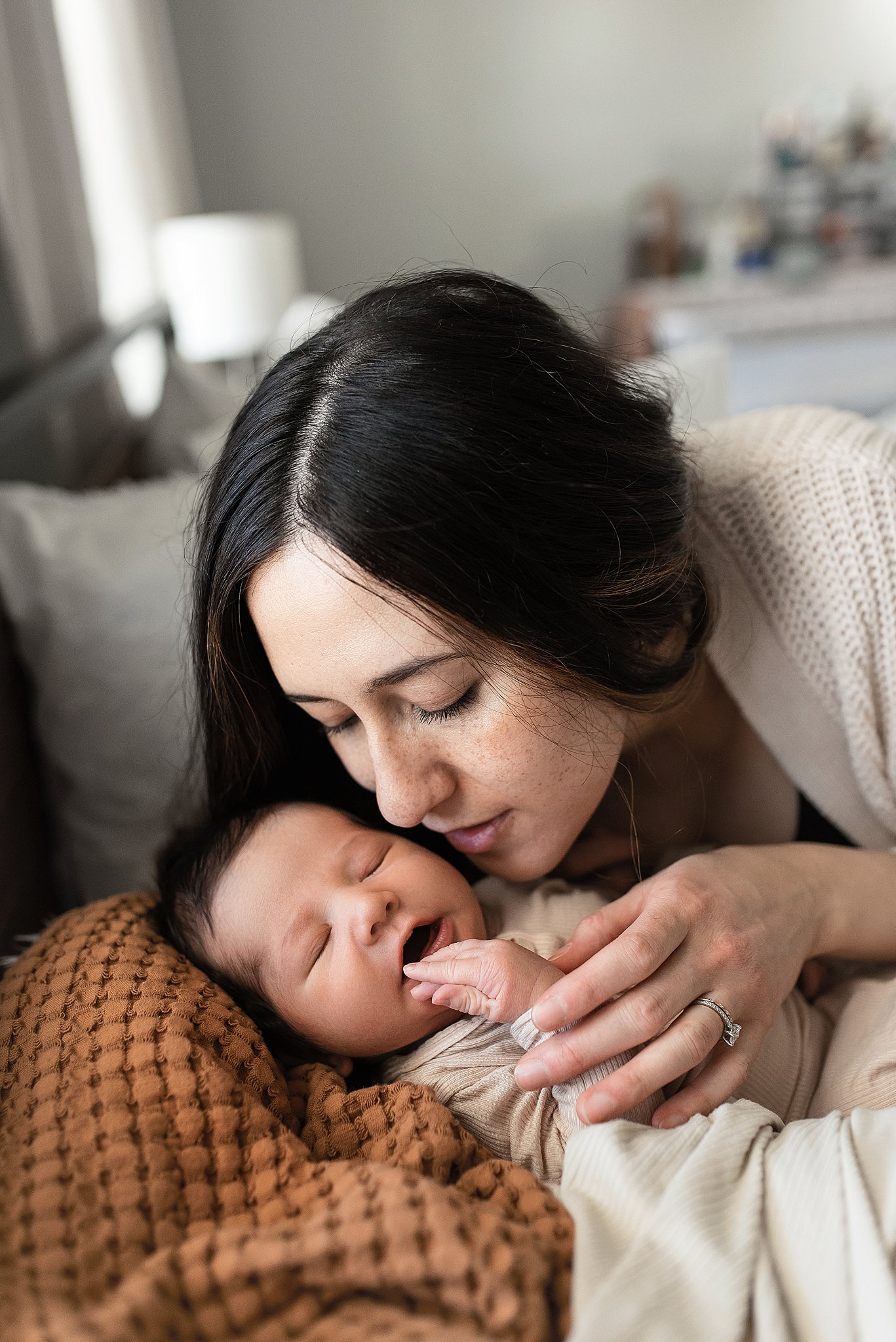 A mother leans over to kiss the cheek of her sleeping newborn baby lactation consultant cleveland ohio